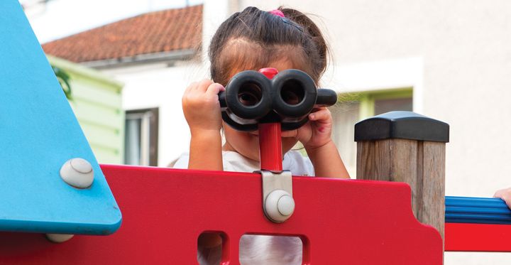 Une petite fille joue sur un jeu dans une cour d'école