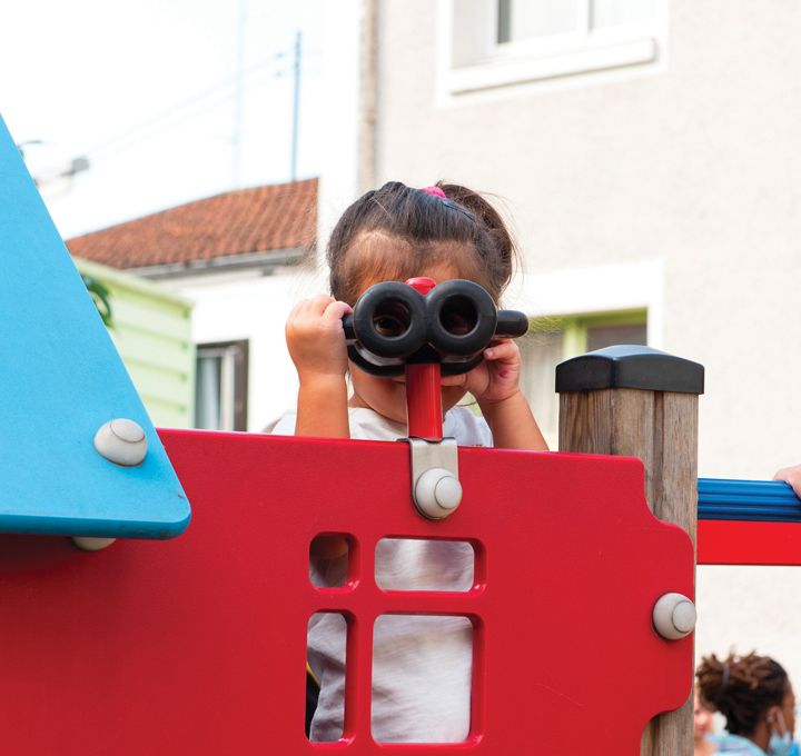 Une petite fille joue sur un jeu dans une cour d'école