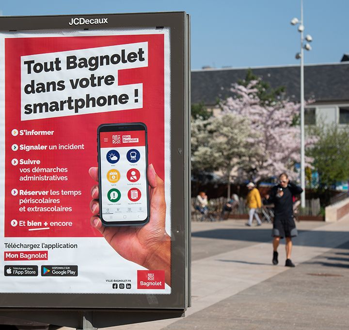 Gros plan sur un panneau d'affichage de l'application Mon Bagnolet sur la place Salvador-Allende au printemps