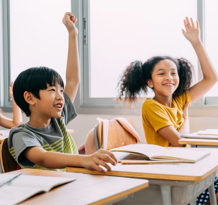 Deux élèves, une fille et un garçon, lèvent la main en classe