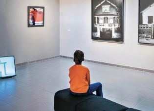Un jeune garçon regarde des photographies de la collection départementale d’art contemporain de Seine-Saint-Denis